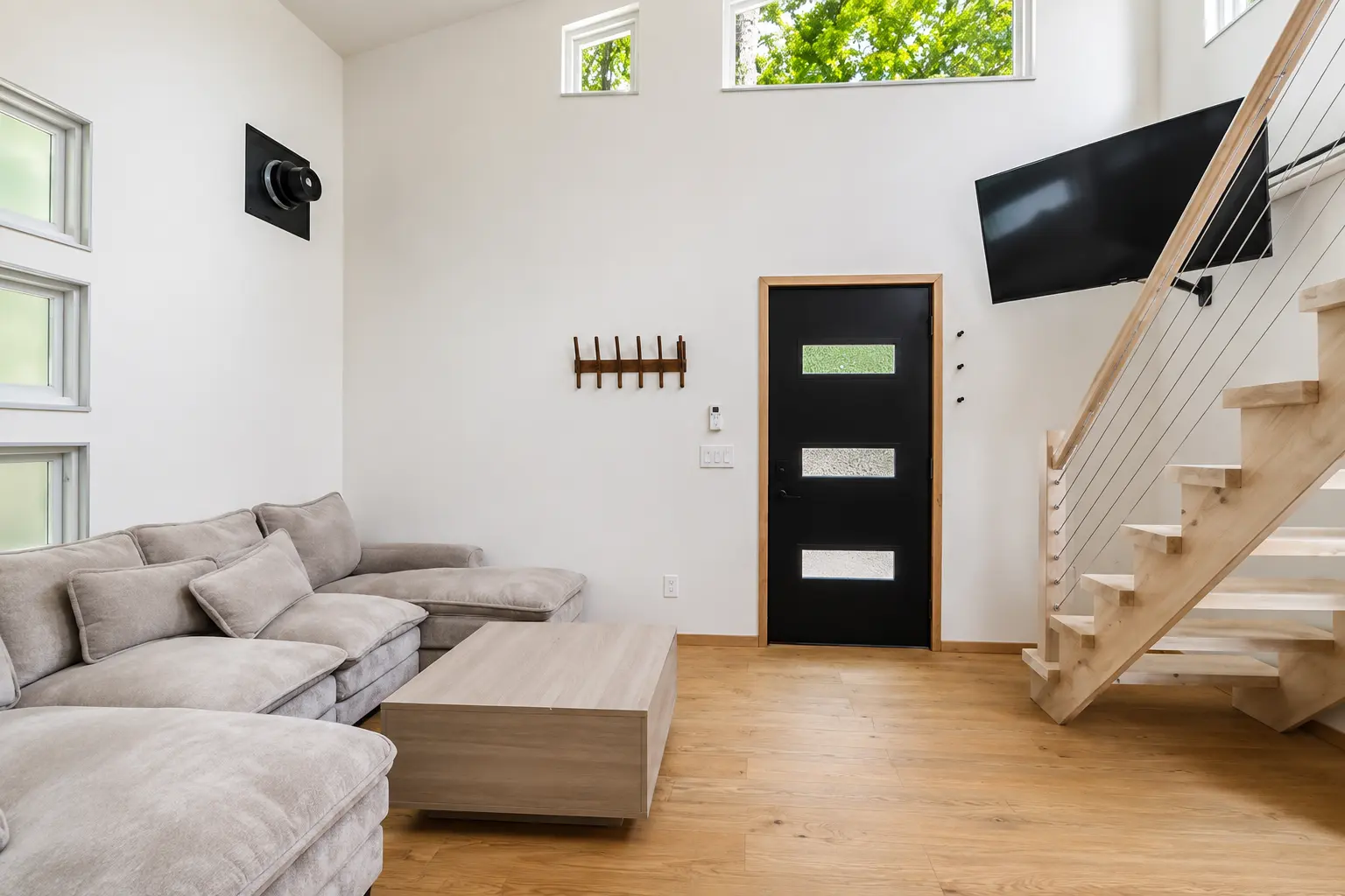 Entry door, wall-mounted TV and wood stairs to the loft