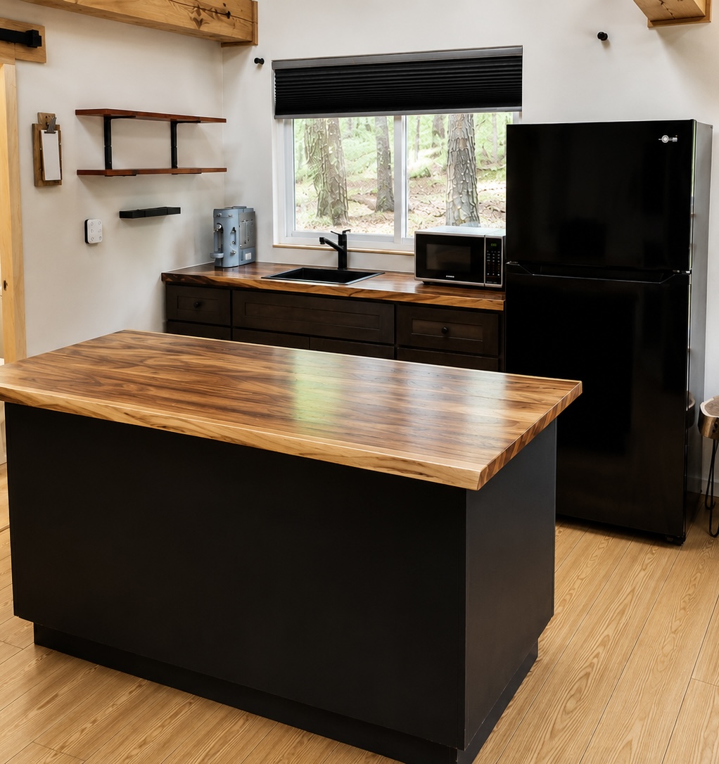 Kitchen island with live-edge walnut top, black cabinets and refrigerator