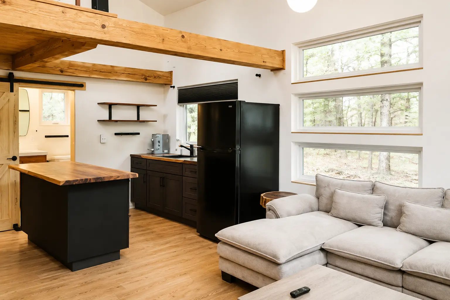 Open living and kitchen area with exposed beams and clerestory windows