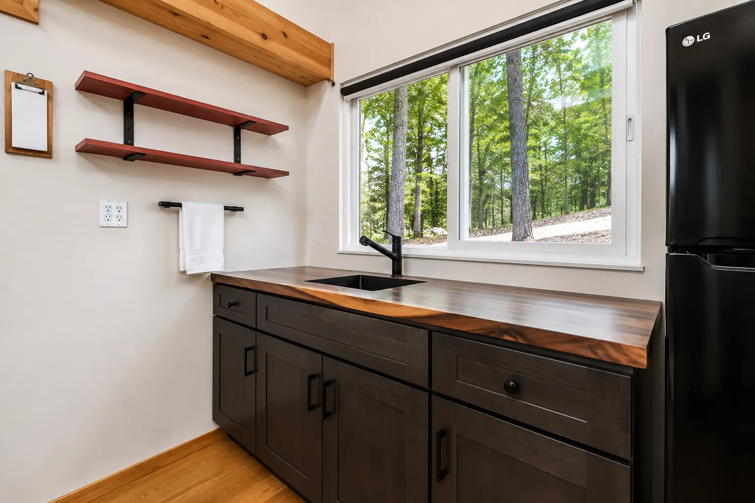 Kitchen with live-edge walnut counter, dark cabinets and forest window
