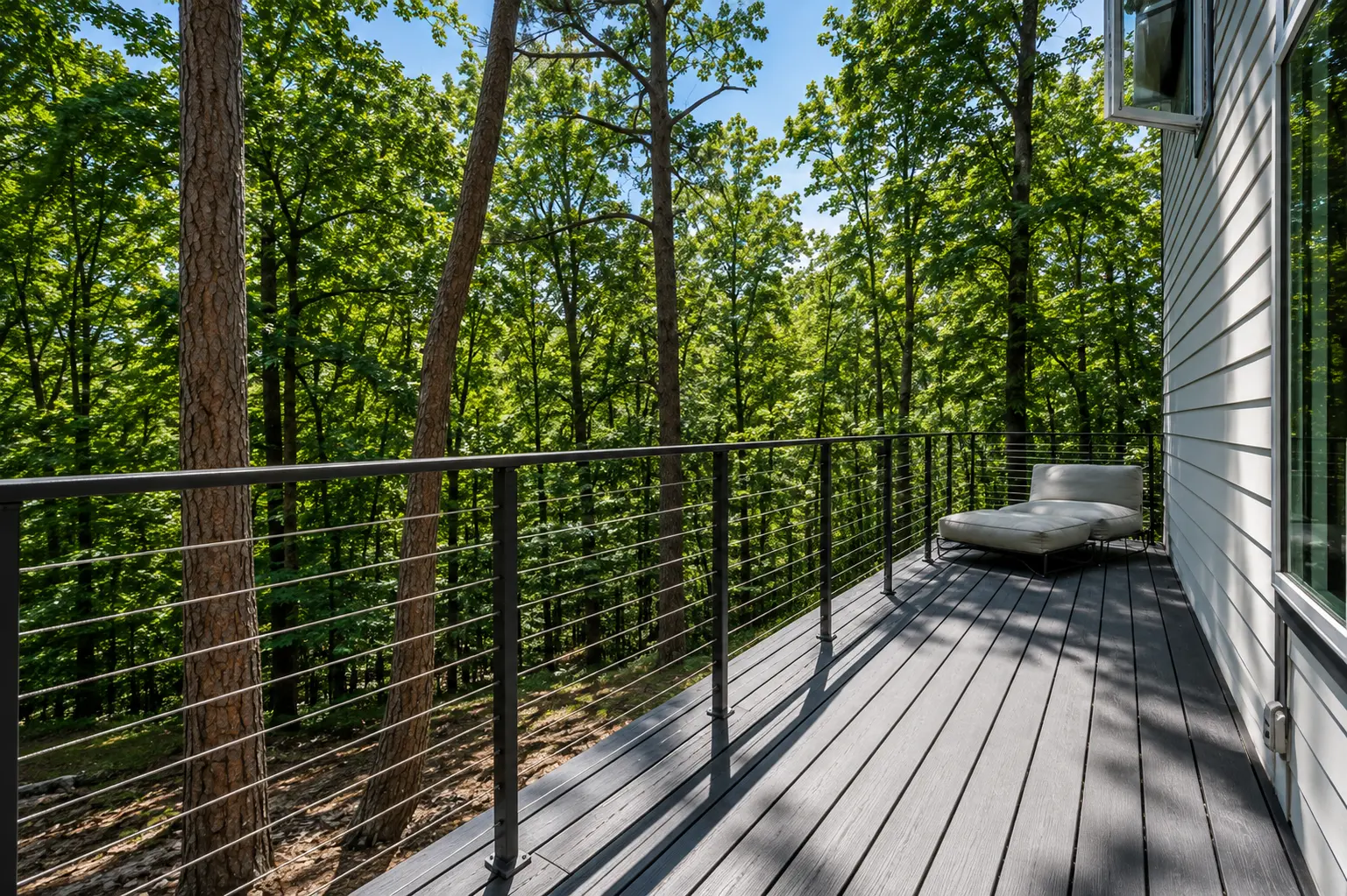 Long view down the deck with cable railing and tall pines