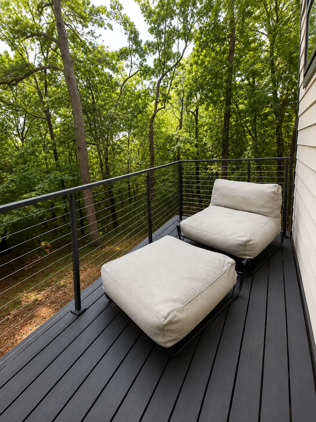 Cushioned lounge chair and ottoman on the deck facing the treetops