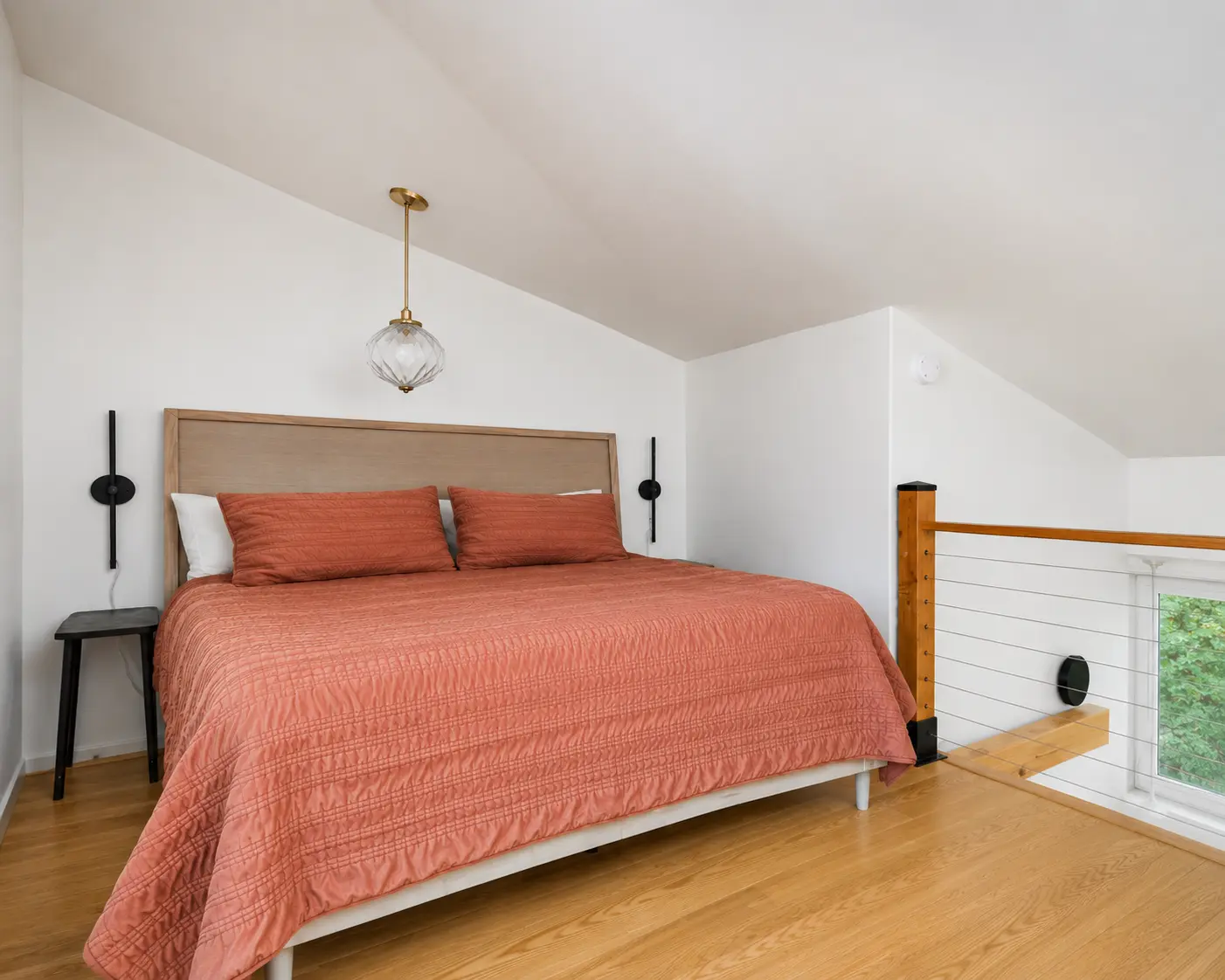 Loft bedroom with a queen bed under a vaulted ceiling