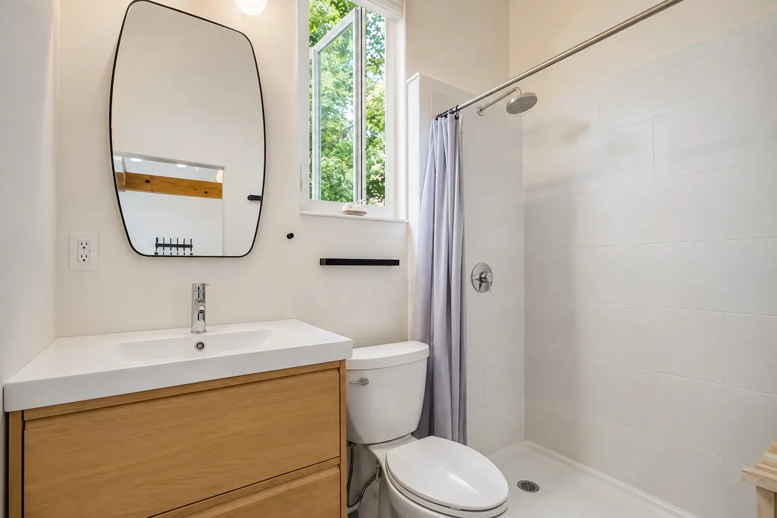 Bathroom with wood vanity, curved mirror and walk-in shower