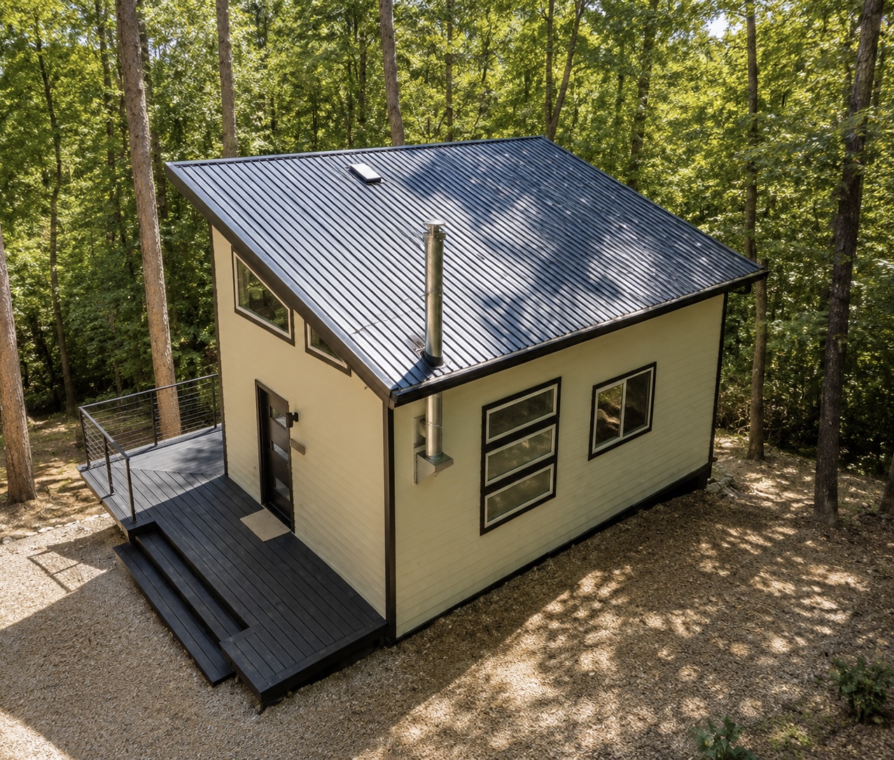 Cabin exterior from above showing metal roof and deck in the trees