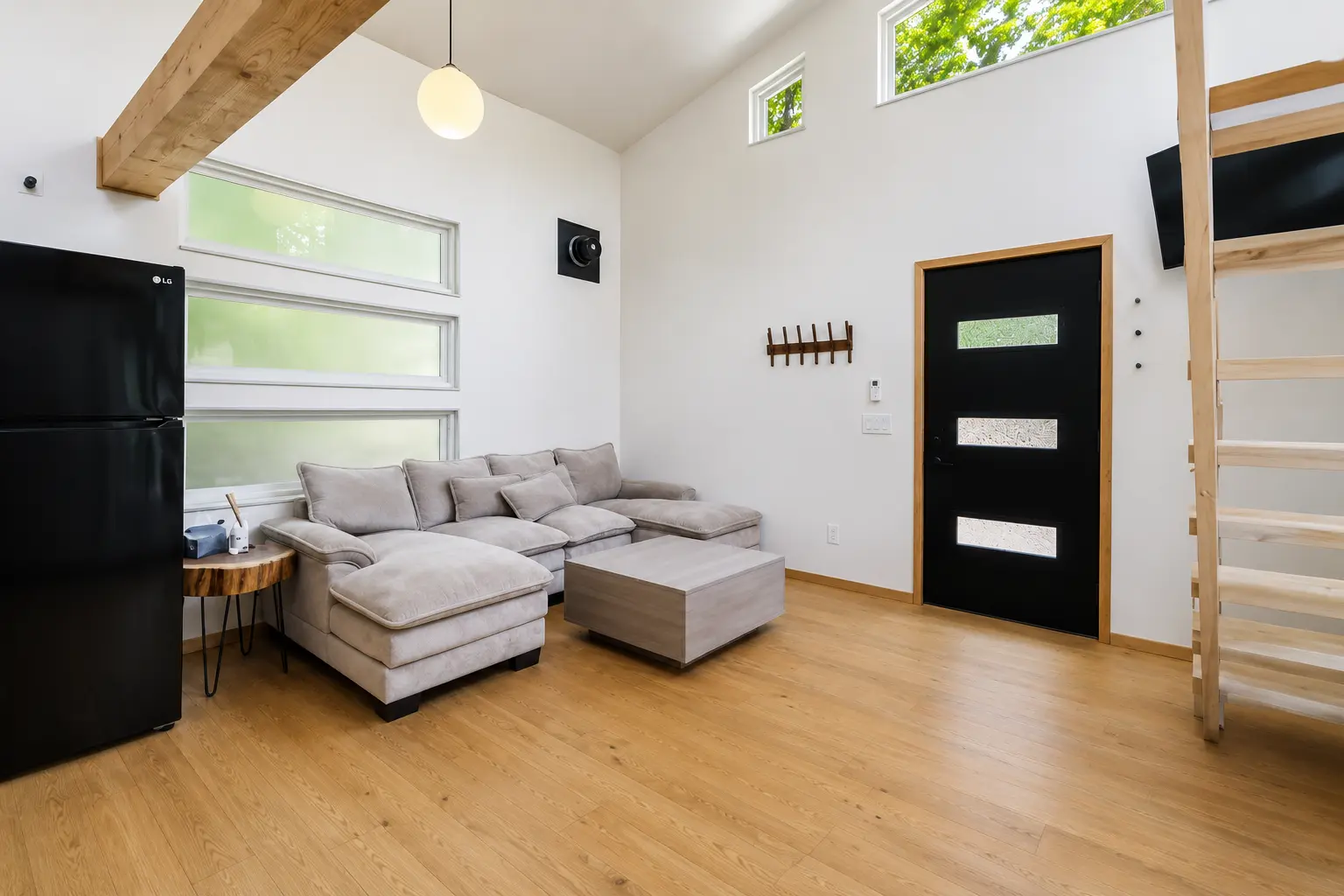 Living room with sectional sofa, loft stairs and forest windows